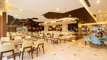 A spacious hotel lobby with multiple seating areas, a central bar, and a modern ceiling design.