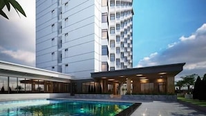 Um hotel moderno com piscina, um edifício alto com varandas e céu claro.