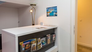 A reception desk with a white counter and a shelf below displaying various brochures. - Rooms and Apartments Bruno (Split)