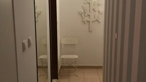 A narrow hallway with a mirrored wardrobe, a small white bench, and a decorative wall piece. - Rooms and Apartments Bruno (Split)