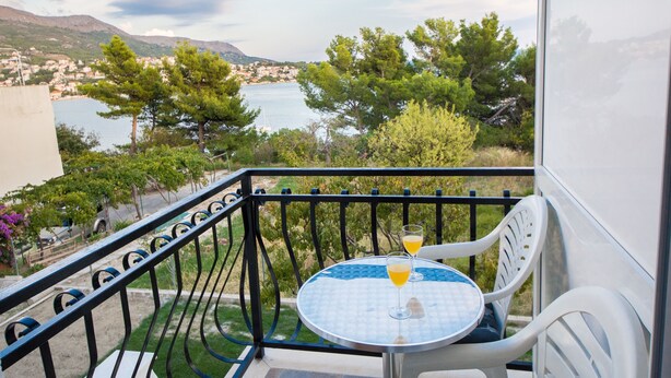 A balcony with a table and chairs, overlooking a body of water and a town. - Rooms and Apartments Bruno (Split)