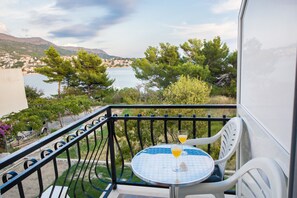 A balcony with a table and chairs, overlooking a body of water and a town. - Rooms and Apartments Bruno (Split)