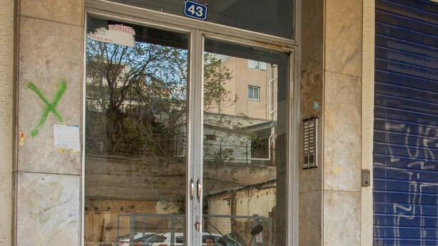 A building entrance with a glass door, a number 43 sign, and a blue shutter door.