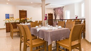 A dining area with wooden chairs and tables, a column, and a floral wall decoration. - Marina Luxury Vung Tau (Ho Chi Minh City)