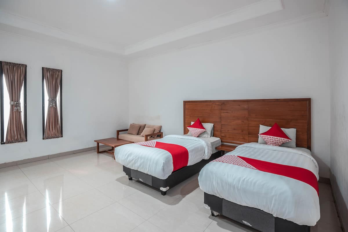 A hotel room with two beds, a sofa, and a wooden headboard.