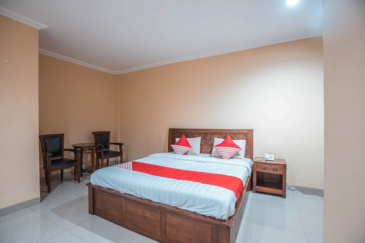 A bedroom with a wooden bed, two chairs, a nightstand, and a small table.