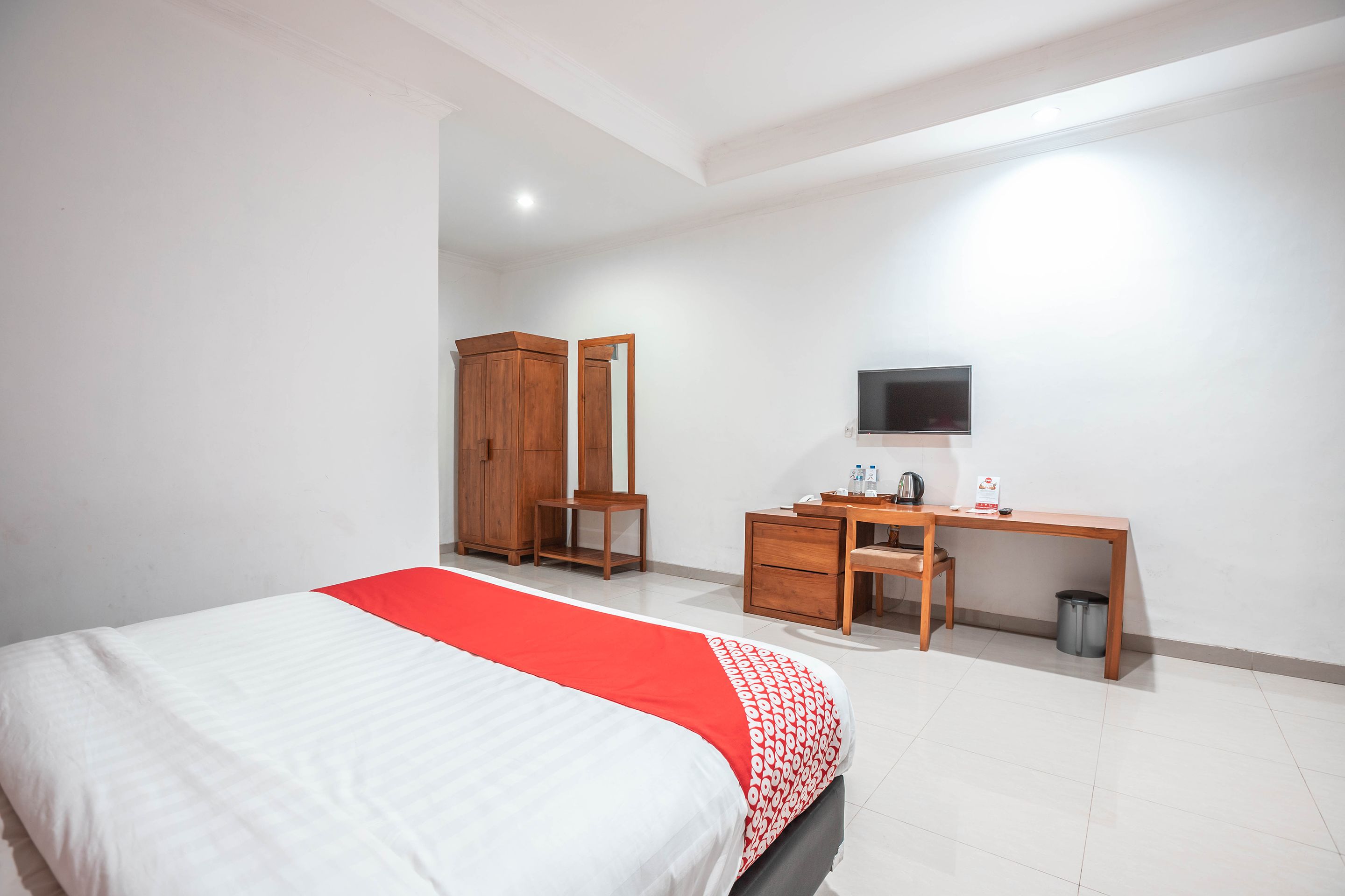 A bedroom with a bed, a desk, a chair, a television, and a wardrobe.