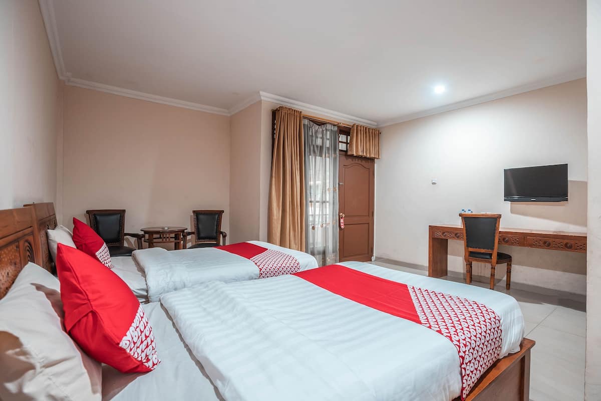 A hotel room with two beds, a desk, a chair, a television, and a door with curtains.