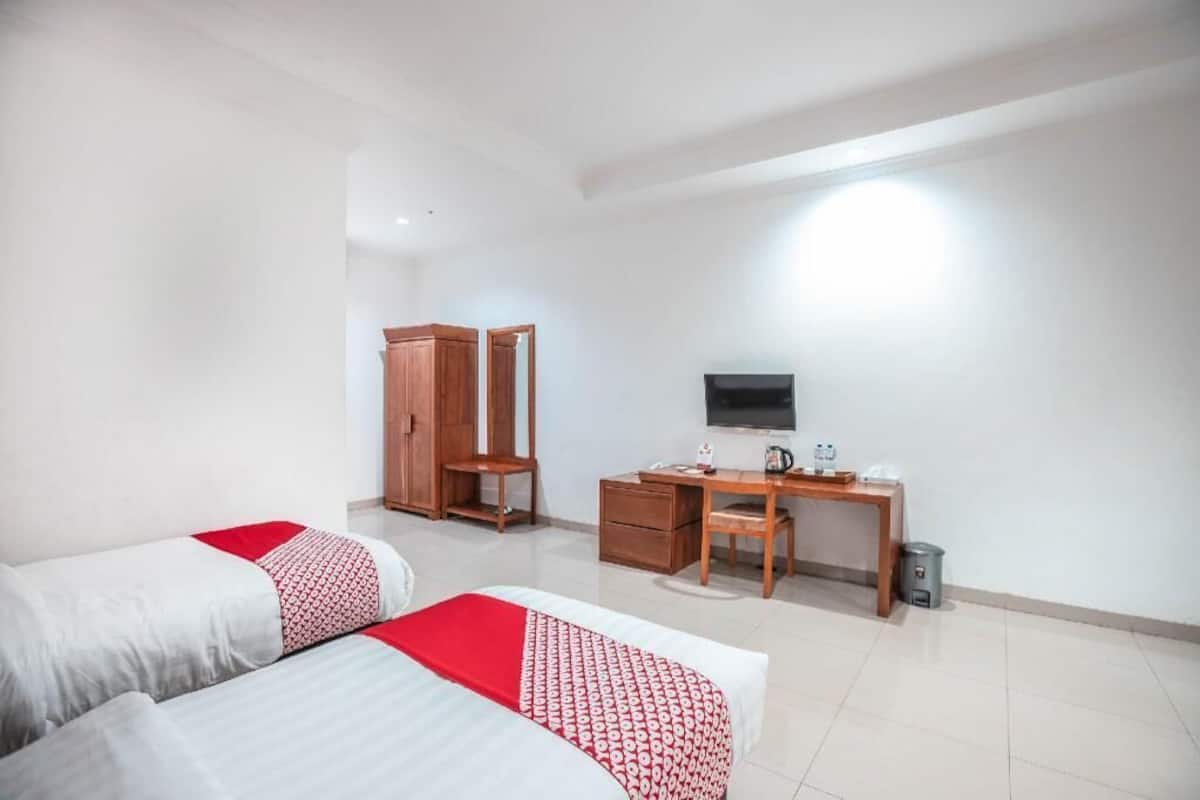 A hotel room with two beds, a desk, a television, and a wardrobe.