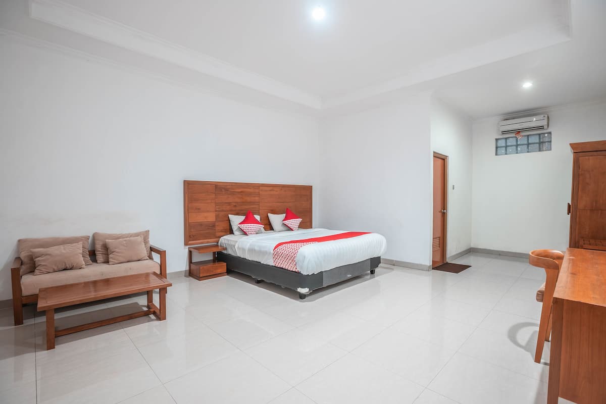 A bedroom with a bed, a wooden bench, a wooden nightstand, a wooden table, and a wooden wardrobe.