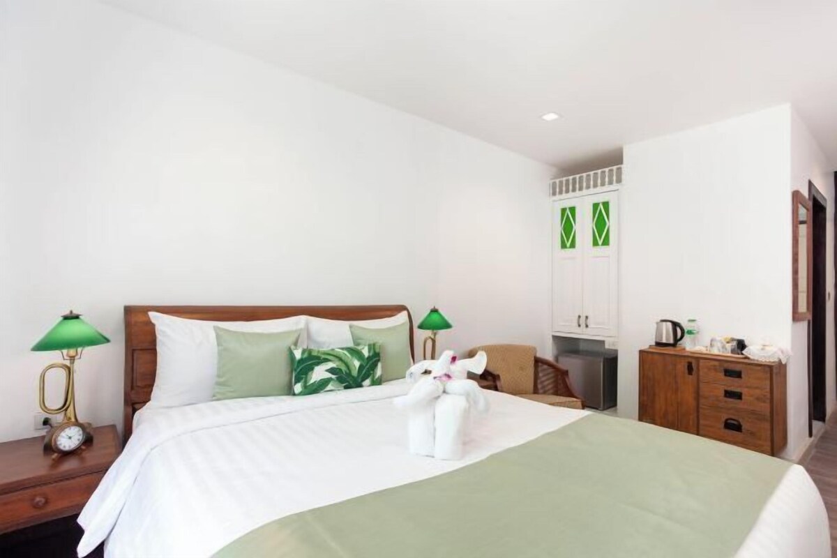 Una habitación de hotel con cama, mesitas de noche, armario y una pequeña kitchenette.