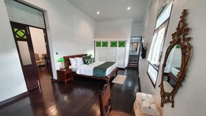 A hotel room with a bed, bedside table, chair, and a mirror. - Sound Gallery House - Hostel (Phuket)