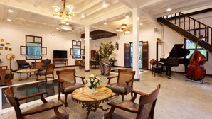 A spacious lobby with a grand piano, a cros - Sound Gallery House - Hostel (Phuket)