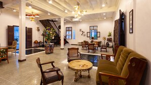 A spacious lobby with a staircase, wooden furniture, and a large vase of flowers. - Sound Gallery House - Hostel (Phuket)