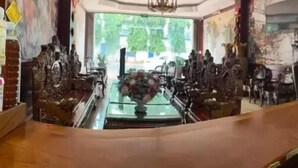 A bar area with a long counter, chairs, and various items like bottles and containers on the shelves.