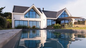 A modern house with a swimming pool reflecting the building and surroundings. - Villa with pool, ocean view (Batz-sur-Mer)