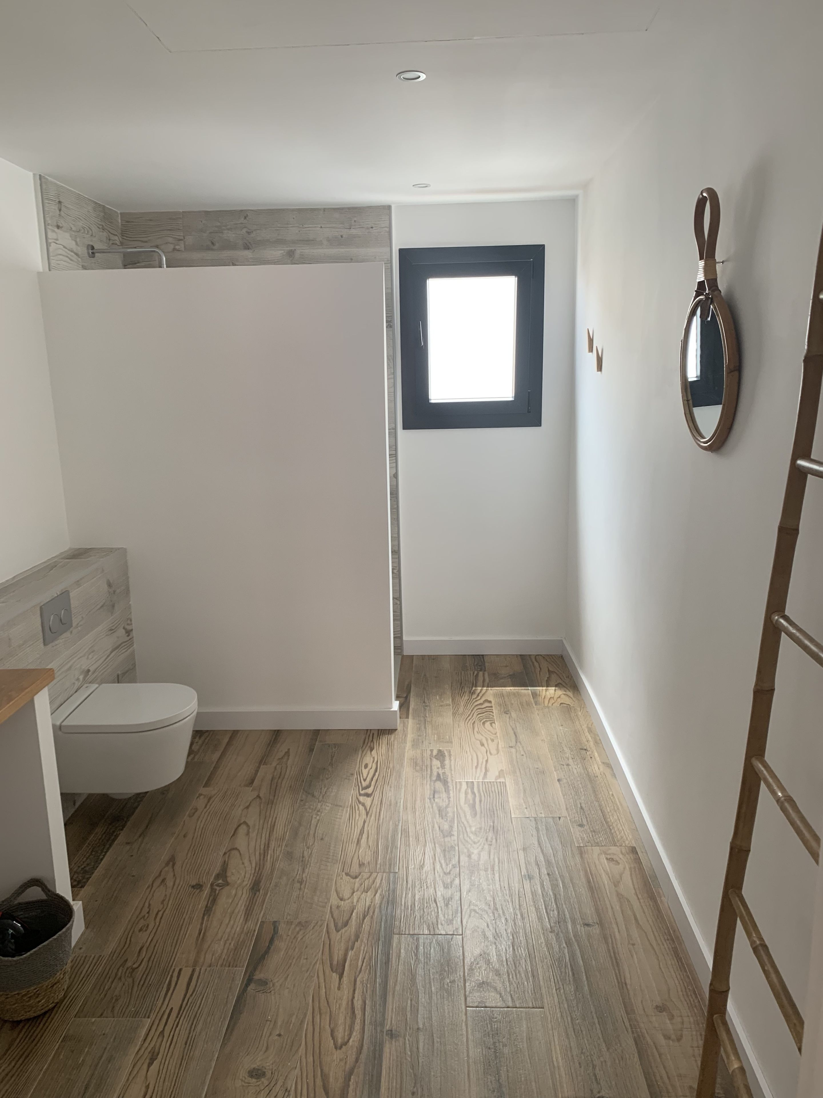 A small, modern bathroom with a toilet, shower, and a window.