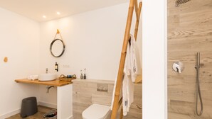 A bathroom with a wooden vanity, a toilet, a shower, and a towel rack. - Pardela Menorca Hotel (Es Castell)