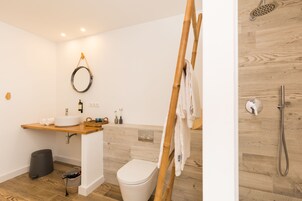 Un baño con tocador de madera, inodoro, ducha y toallero.