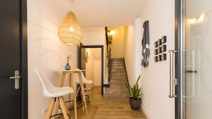 A hallway with a staircase, a dining area with chairs and a table, and a potted plant. - Pardela Menorca Hotel (Es Castell)