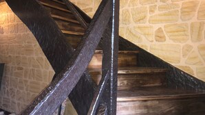 Una escalera con barandillas de madera oscura y paredes de piedra.