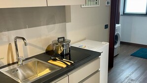 Une cuisine compacte équipée d’un évier en acier inoxydable, d’une machine à café et d’une casserole posée sur le plan de travail.