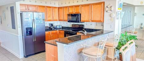 A modern kitchen with wooden cabinets, stainless steel appliances, and a central island with bar stools.