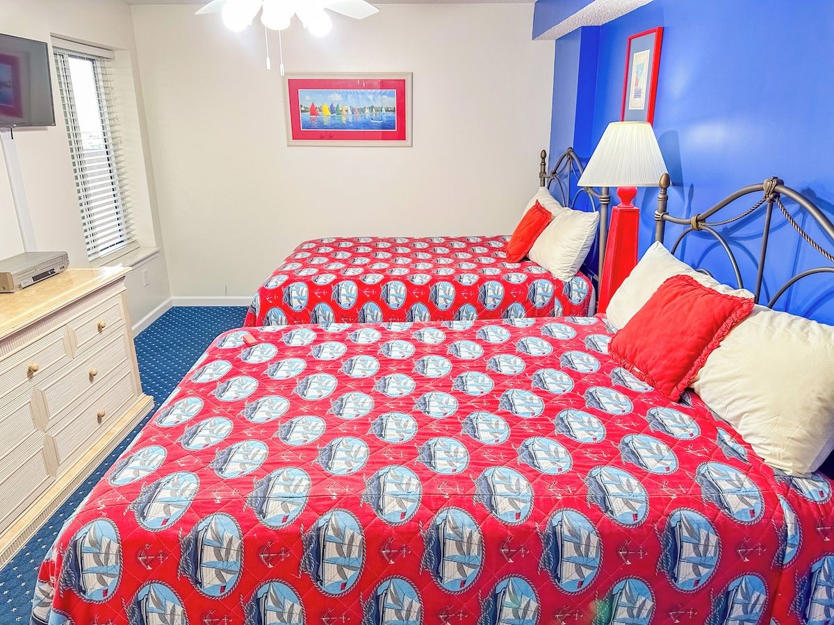 A bedroom with two beds, a dresser, a window with blinds, a painting on the wall, and a lamp.