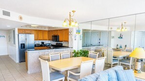 Une cuisine moderne avec des meubles en bois, un îlot central et un coin repas avec des chaises blanches.