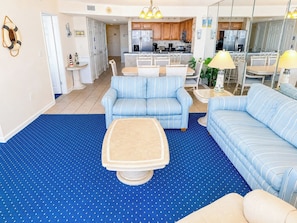 A living room with striped sofas, a coffee table, and a blue carpet. - Crescent Shores S 210 (North Myrtle Beach)