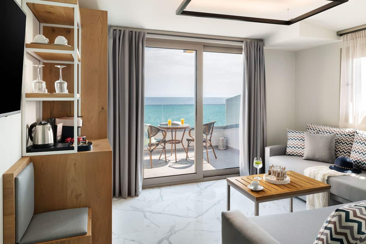 Una habitación de hotel moderna con balcón, sofá, mesa de centro y televisor.