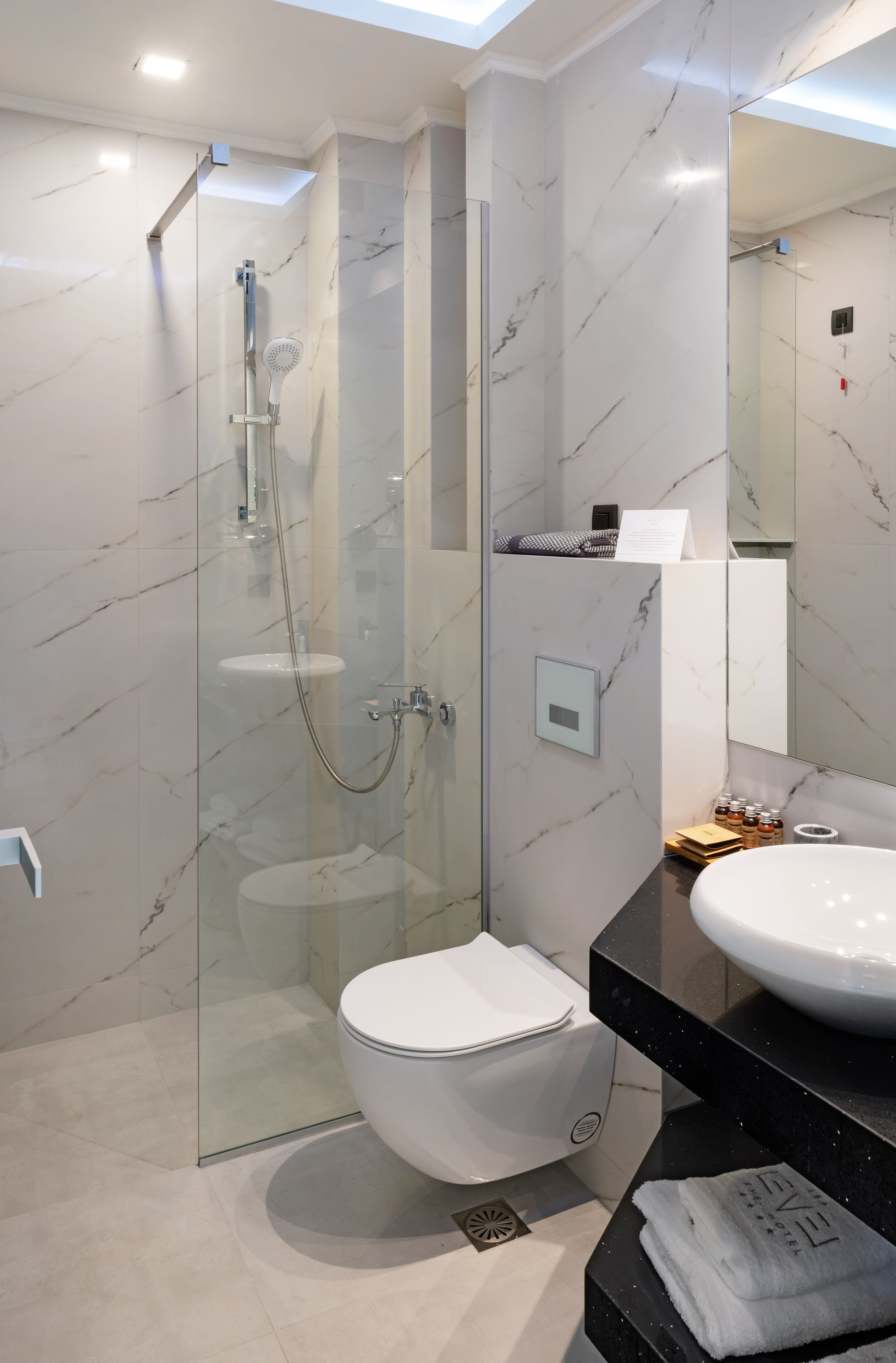 Een moderne badkamer met een douchecabine van glas, een wit toilet en een zwart aanrecht met een wastafel.