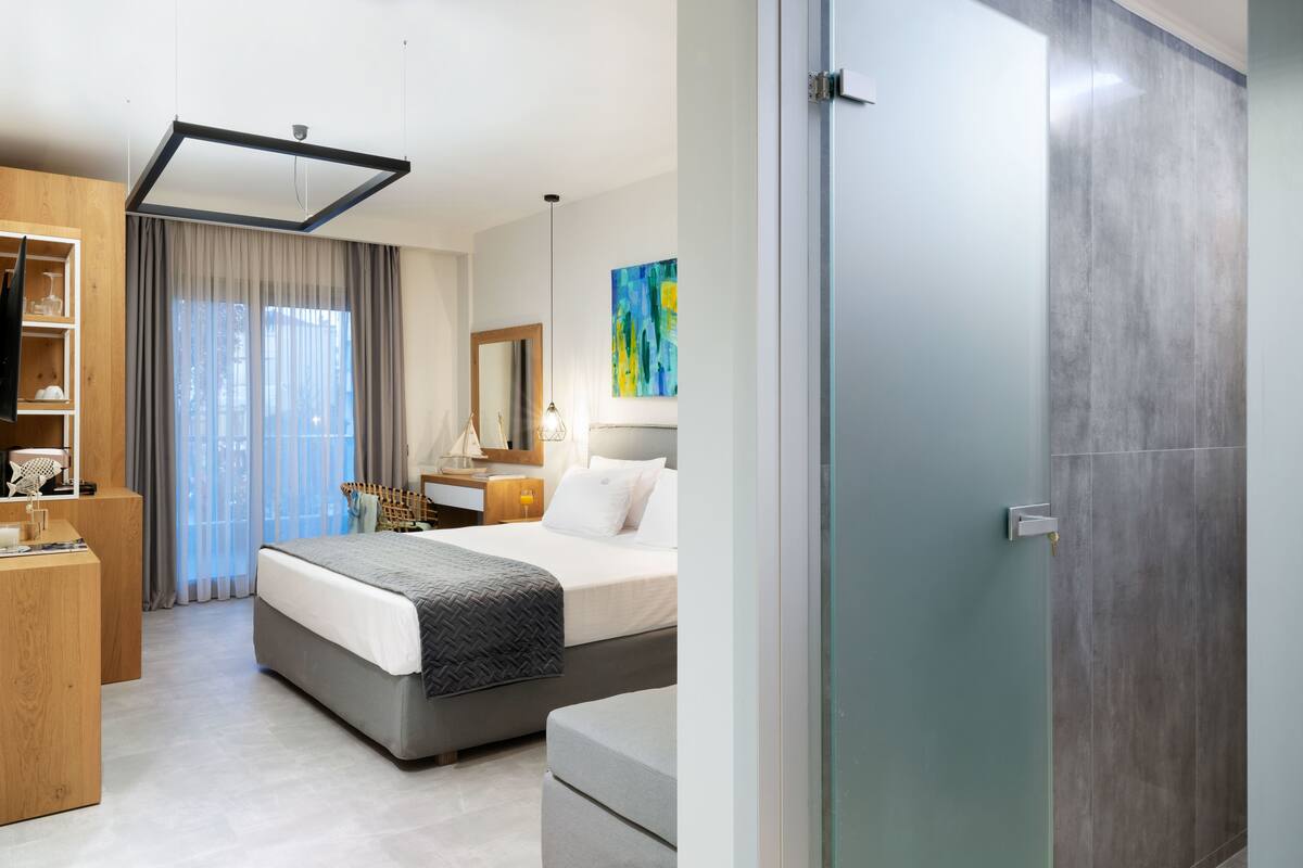 Una habitación de hotel moderna con una cama, mesita de noche y un escritorio con silla.
