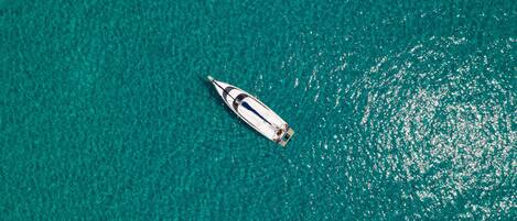 An aerial view of a boat on clear turquoise water.