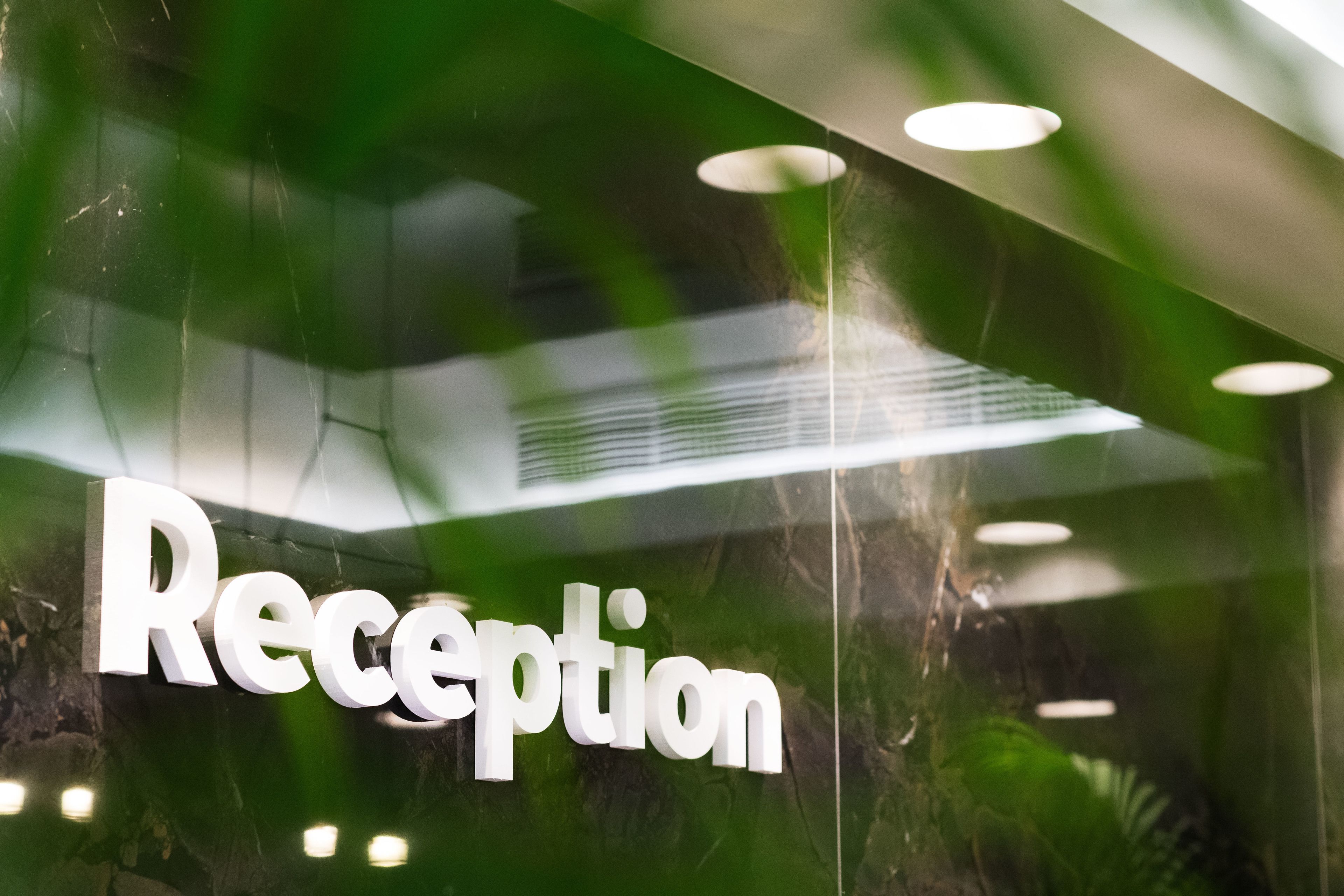 A reception area with a glass wall and a sign that reads "Reception".