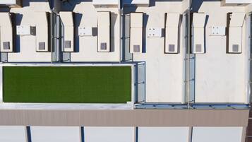 Une façade de bâtiment moderne, dotée de nombreuses fenêtres rectangulaires et d’une section de gazon synthétique vert.