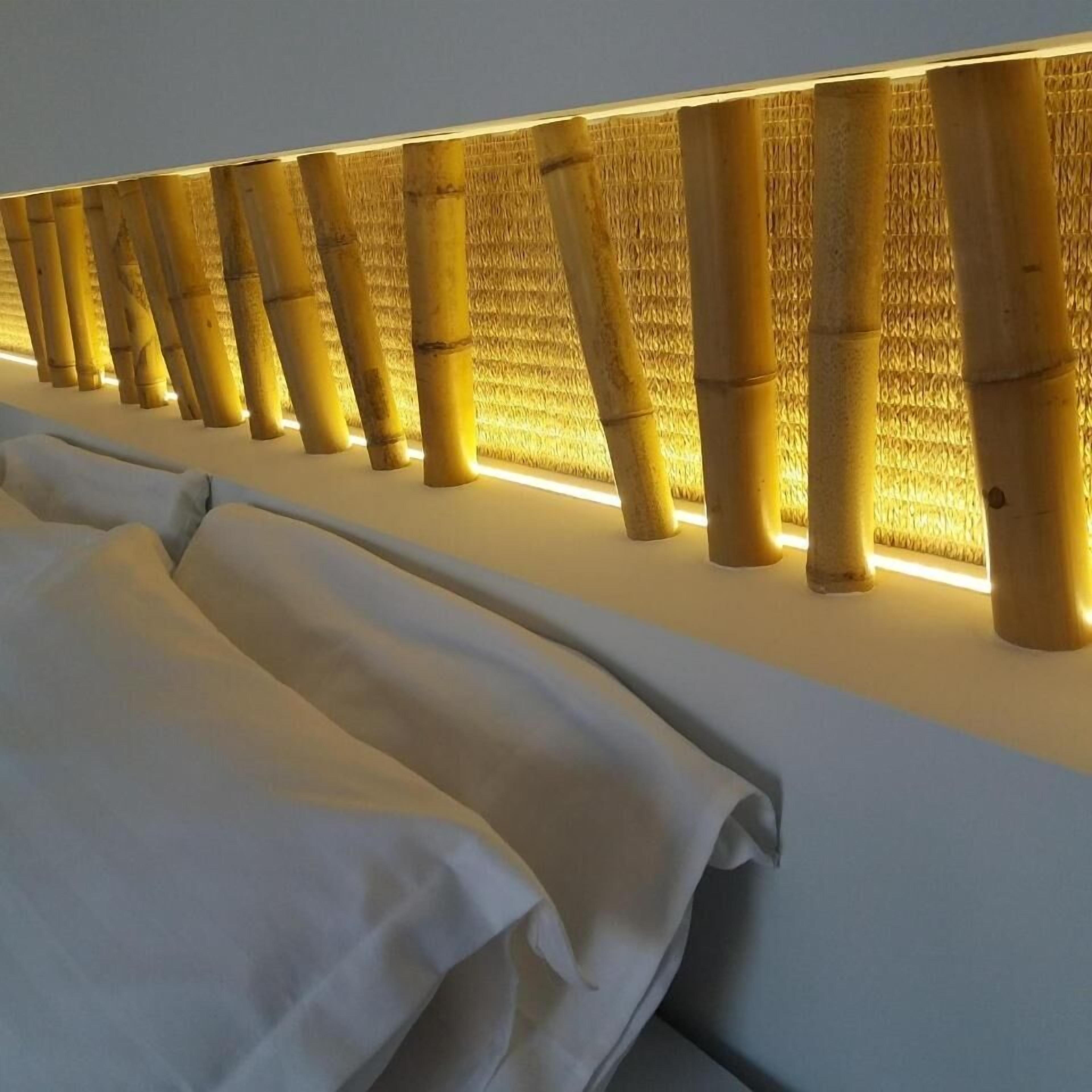 A hotel room with a bamboo wall feature and neatly arranged beds.