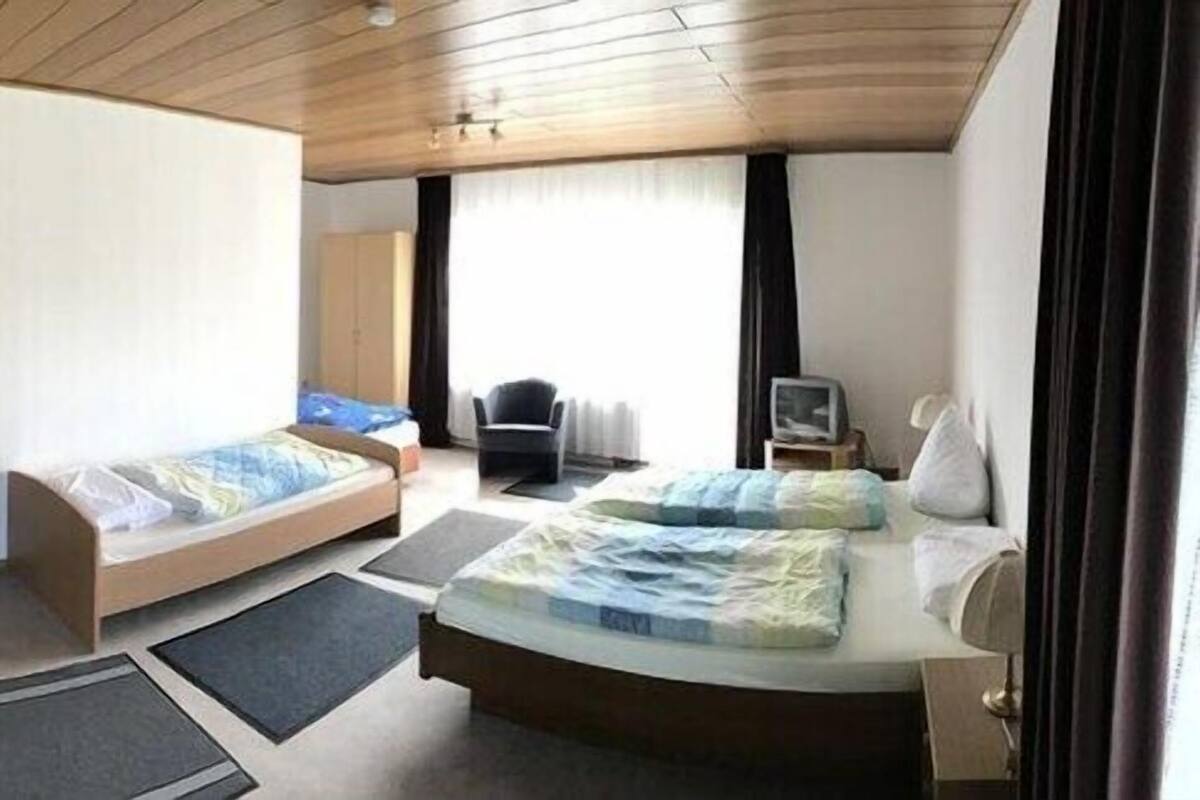 A compact room with a sofa, a small desk, a bed, and a chair.