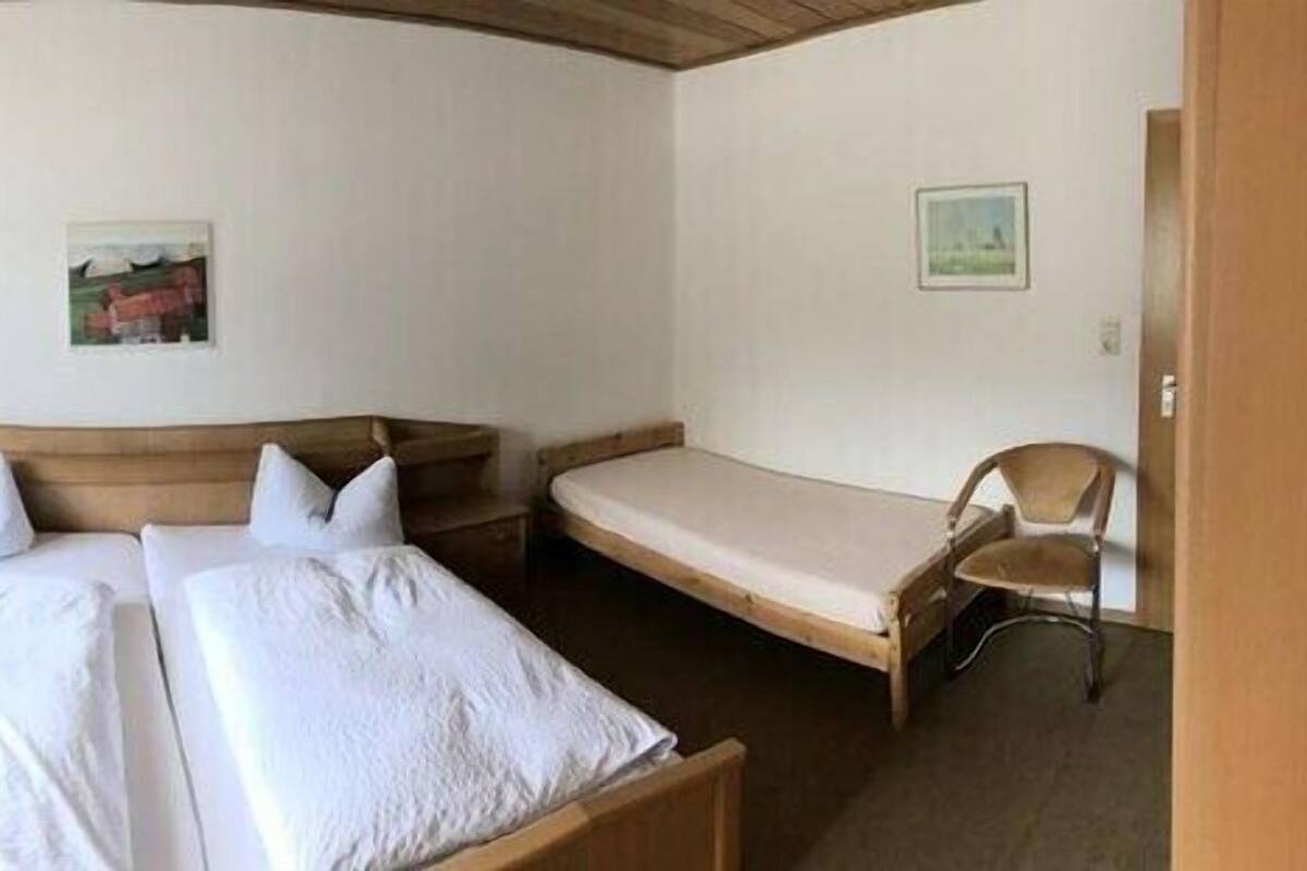 A hotel room with a double bed, a desk with a chair, a TV, and a window with curtains.