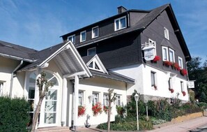 A two-story building with a gabled roof, large windows, and a balcony with red flowers. - Hotel Dribischenhof (Willingen)