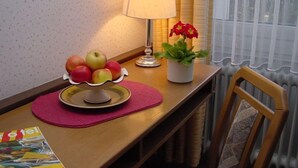 Una mesa con un frutero, una lámpara y una planta en maceta.
