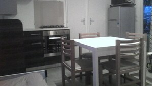 Una cocina compacta con estufa, armarios y una mesa de comedor con sillas.
