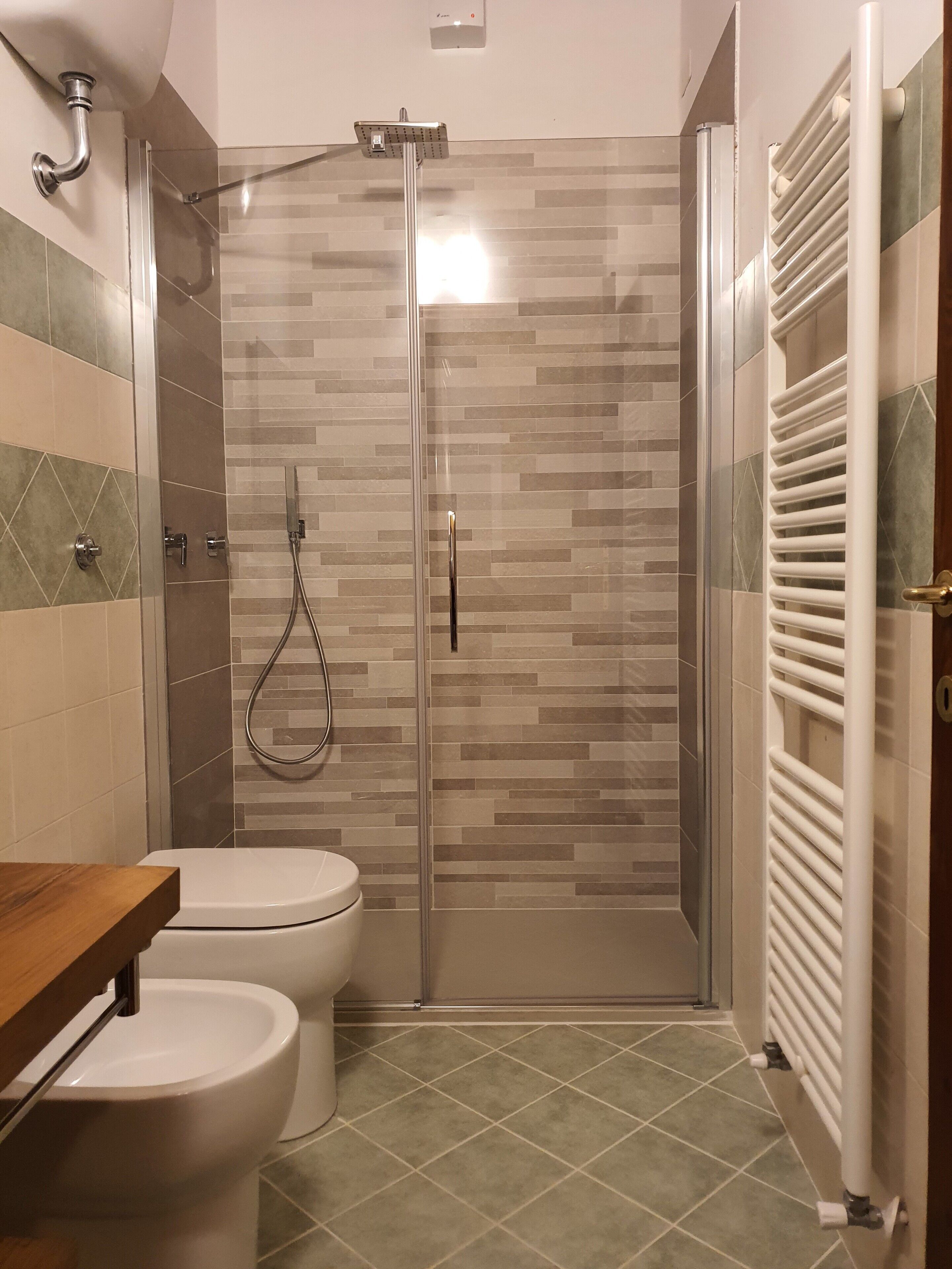A bathroom with a shower, toilet, and a towel rack.