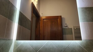 A bathroom with a wooden door, a towel rack, and a light fixture on the wall.