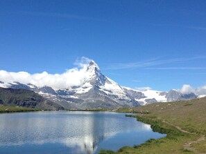 Un pico montañoso con un lago al frente y un cielo despejado.