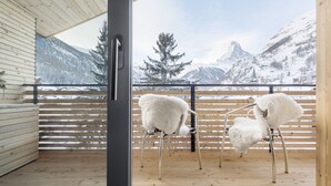 En interiör med träinredning och en balkong med utsikt över ett snöklätt berglandskap.