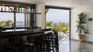 Zona de bar con vistas al océano, una planta en maceta y un cartel que indica bar de piscina.