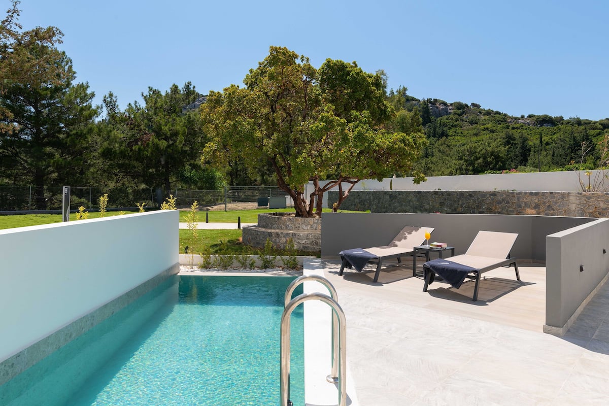 Un espace piscine offrant une vue dégagée sur le paysage environnant, notamment sur les arbres et une colline située au loin.