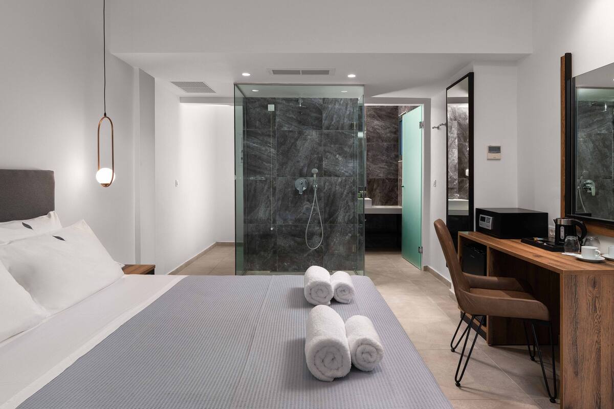 Une chambre d’hôtel moderne équipée d’un lit, d’un bureau, d’une douche et d’un grand miroir.