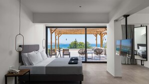 Un dormitorio moderno con una cama grande, televisor y vista al mar a través de un ventanal corredero.